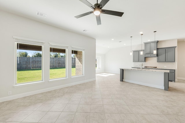 unfurnished living room with a wealth of natural light, sink, light tile patterned floors, and ceiling fan