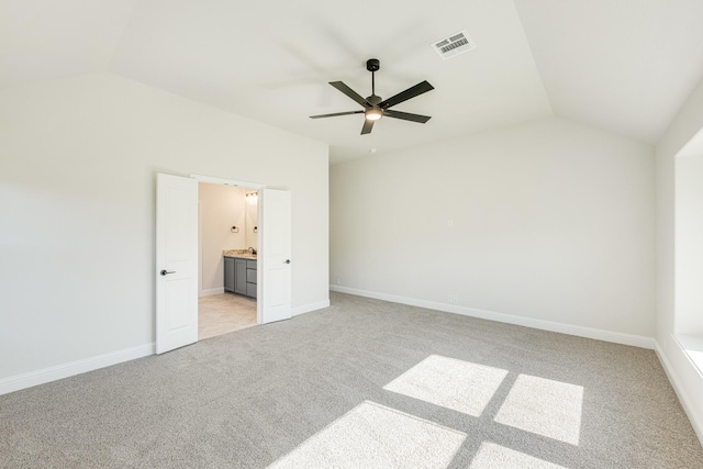 unfurnished bedroom with ceiling fan, light colored carpet, connected bathroom, and vaulted ceiling