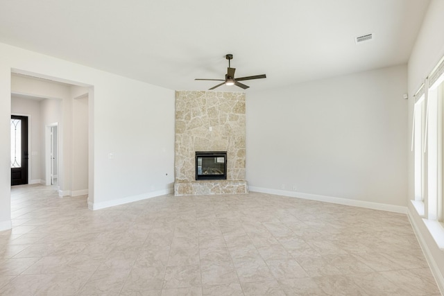 unfurnished living room with ceiling fan and a stone fireplace