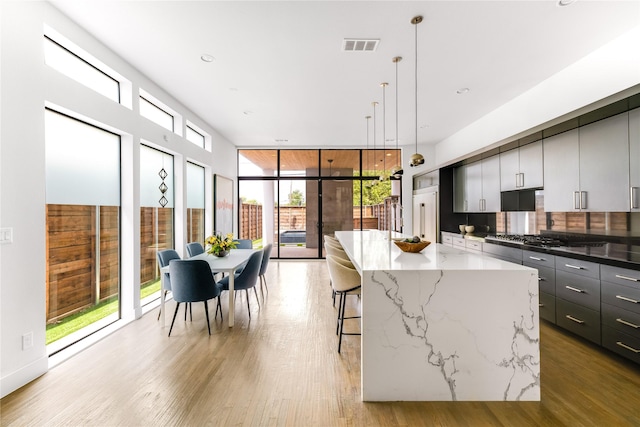 kitchen with tasteful backsplash, modern cabinets, a kitchen breakfast bar, a center island, and light wood-type flooring