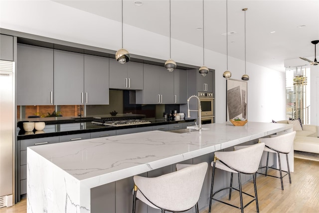 kitchen with stainless steel appliances, gray cabinets, light wood-style floors, a sink, and modern cabinets