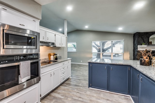 kitchen with blue cabinetry, lofted ceiling, white cabinetry, stainless steel appliances, and light stone countertops