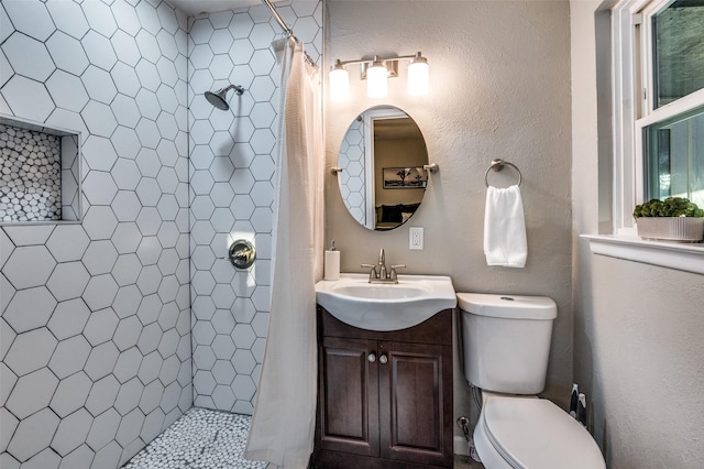 bathroom featuring vanity, toilet, and tiled shower