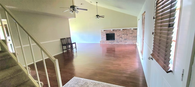 staircase featuring high vaulted ceiling, dark wood-type flooring, ceiling fan, and a fireplace