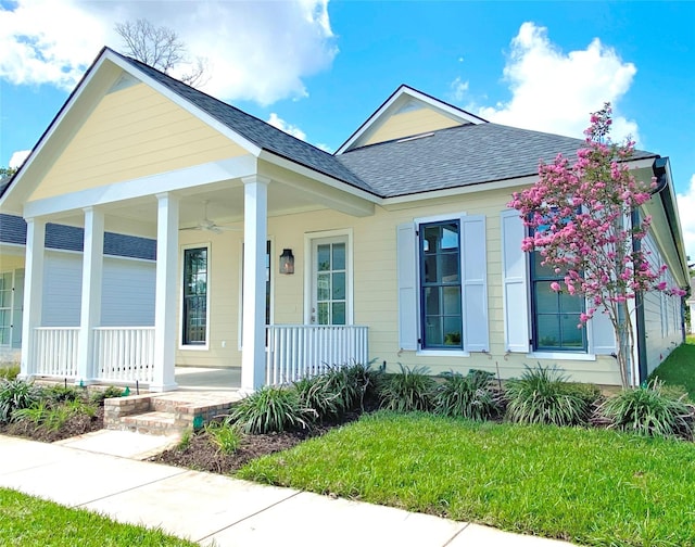 view of front facade with ceiling fan, a porch, and a front yard