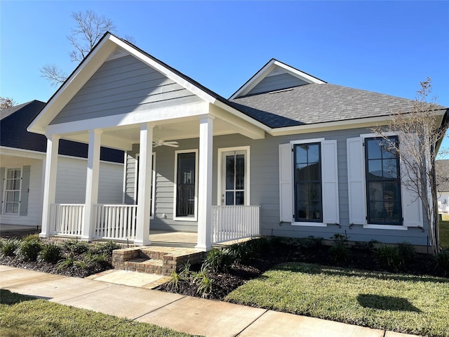 view of front of house with a front yard, roof with shingles, a porch, and a ceiling fan