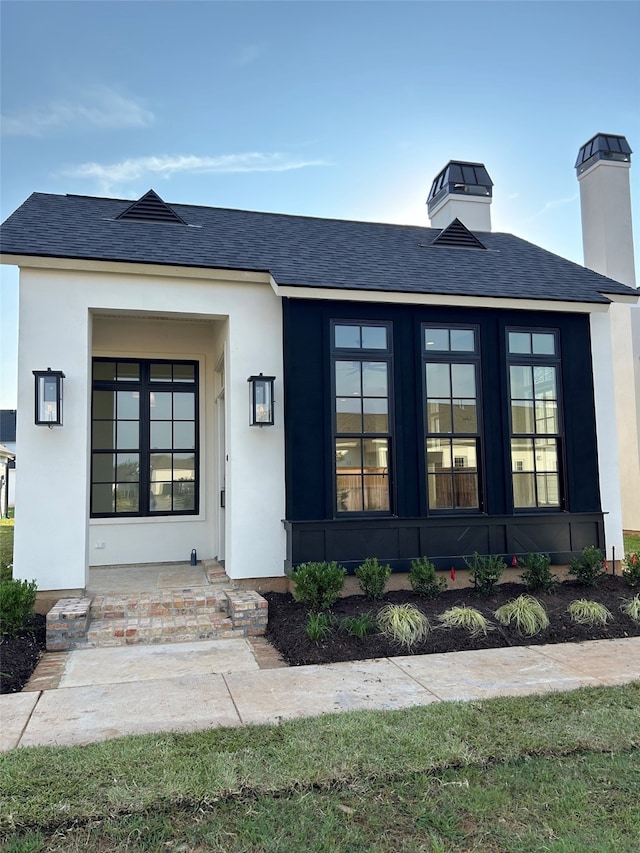 exterior space with a shingled roof, french doors, and stucco siding