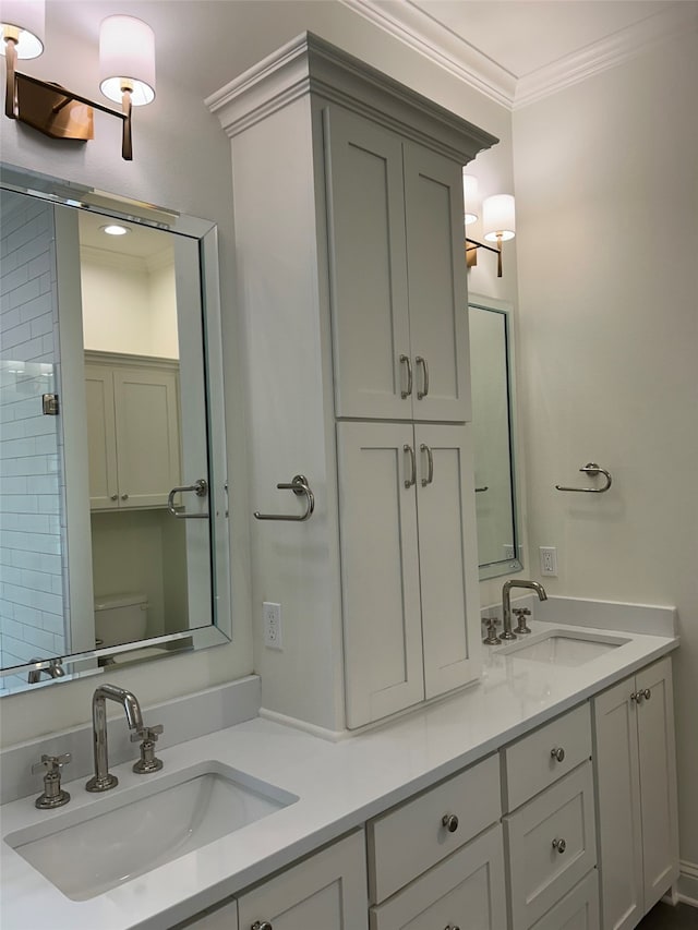 bathroom with double vanity, toilet, crown molding, and a sink