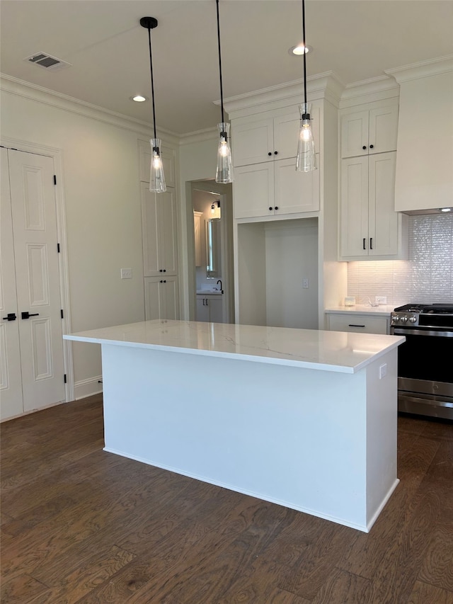 kitchen featuring stainless steel gas range oven, white cabinets, dark wood finished floors, and light countertops