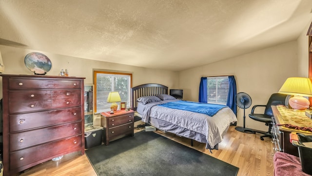 bedroom featuring vaulted ceiling, a textured ceiling, and hardwood / wood-style flooring