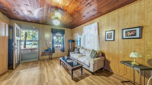 living room featuring wooden ceiling, wood walls, light wood-type flooring, and ceiling fan