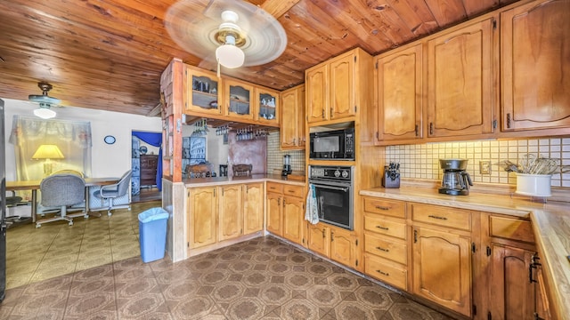 kitchen featuring wooden ceiling, a ceiling fan, light countertops, backsplash, and black appliances