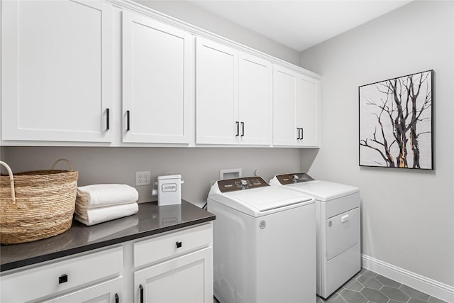 washroom with dark tile patterned flooring, cabinets, and washing machine and dryer