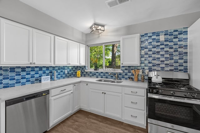 kitchen featuring sink, stainless steel appliances, tasteful backsplash, white cabinets, and hardwood / wood-style floors