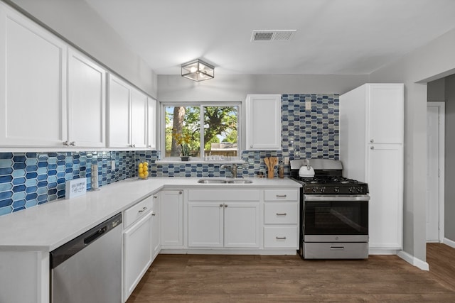 kitchen with appliances with stainless steel finishes, dark hardwood / wood-style flooring, white cabinetry, and sink