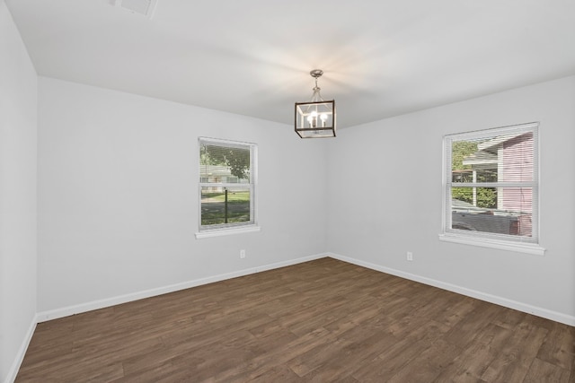 empty room featuring dark hardwood / wood-style flooring and an inviting chandelier