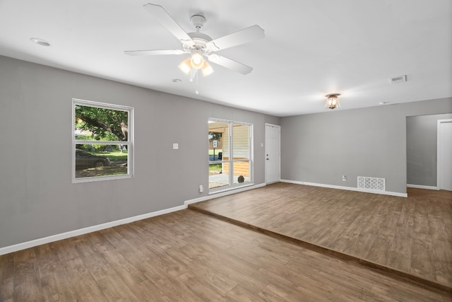 unfurnished room featuring a healthy amount of sunlight, dark hardwood / wood-style floors, and ceiling fan