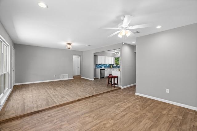 empty room featuring a wealth of natural light, ceiling fan, and light wood-type flooring