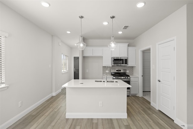 kitchen featuring light wood-type flooring, stainless steel appliances, a kitchen island with sink, sink, and white cabinets