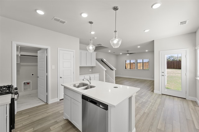 kitchen featuring pendant lighting, stainless steel dishwasher, gas range oven, an island with sink, and white cabinetry