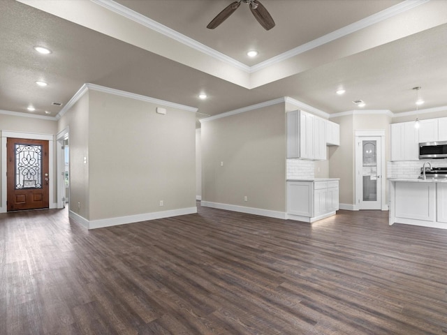 unfurnished living room featuring crown molding, ceiling fan, and dark hardwood / wood-style floors