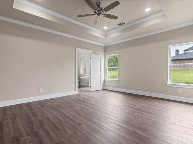 empty room featuring ornamental molding, dark wood-type flooring, ceiling fan, and a raised ceiling