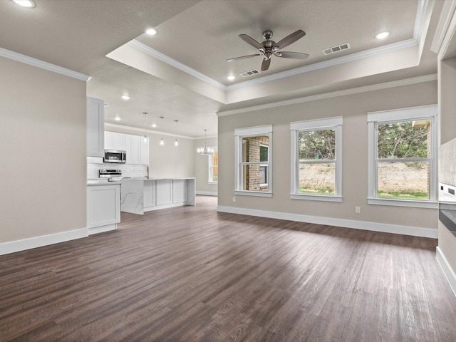 unfurnished living room with ornamental molding, dark hardwood / wood-style flooring, ceiling fan with notable chandelier, and a raised ceiling