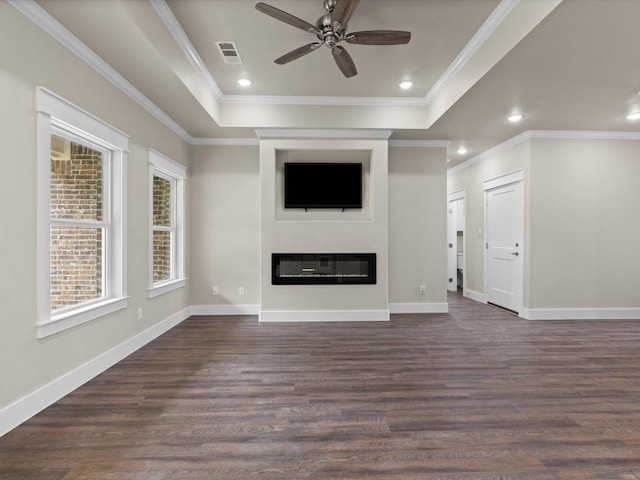 unfurnished living room with ceiling fan, dark hardwood / wood-style flooring, a tray ceiling, and ornamental molding