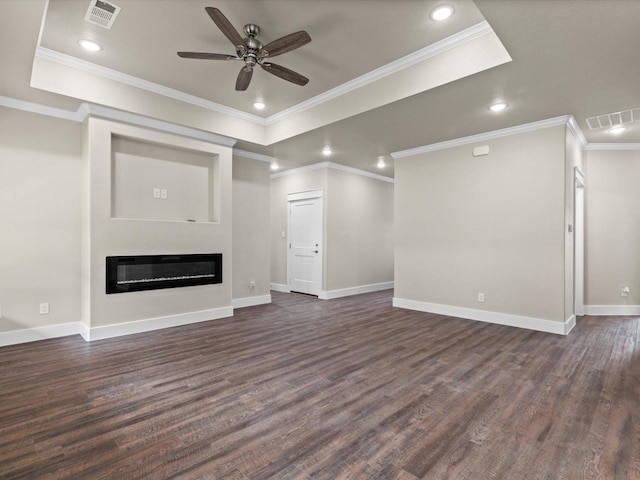 unfurnished living room featuring ceiling fan, crown molding, a tray ceiling, and dark wood-type flooring