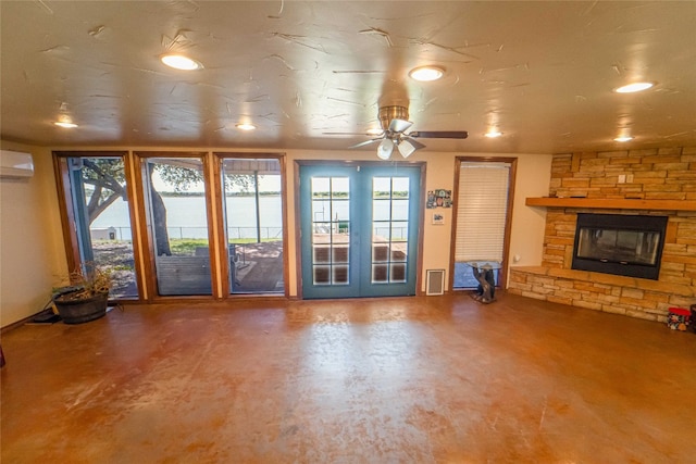 unfurnished living room with french doors, a wall mounted air conditioner, ceiling fan, and a fireplace