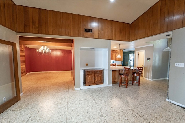 kitchen featuring pendant lighting, a high ceiling, an inviting chandelier, light tile floors, and a breakfast bar area