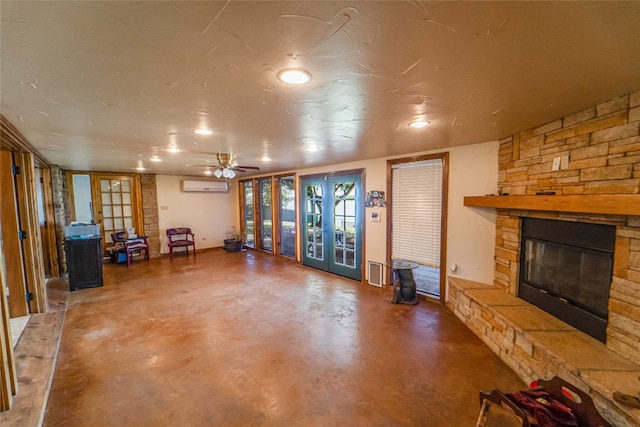 unfurnished living room with french doors, a wall mounted air conditioner, a stone fireplace, and ceiling fan