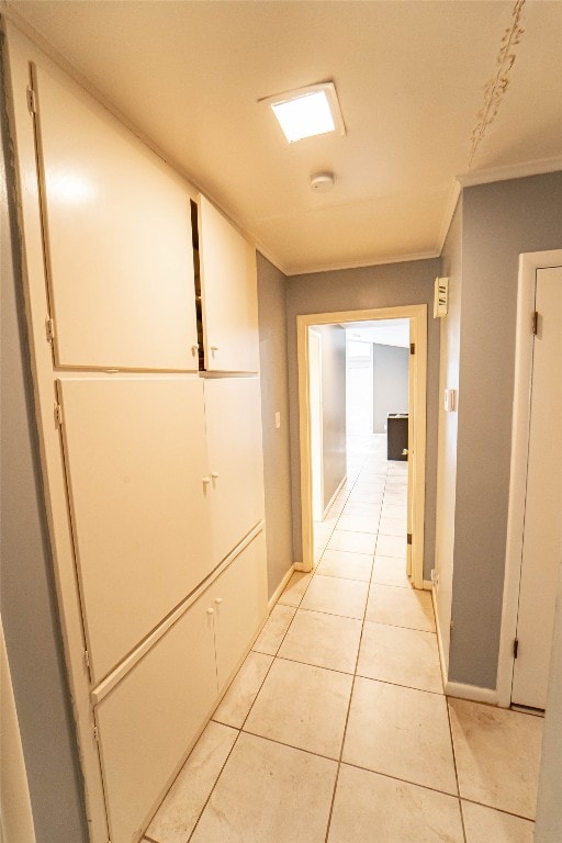 hall with ornamental molding and light tile floors