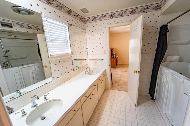 bathroom featuring tile flooring, tile walls, and dual bowl vanity