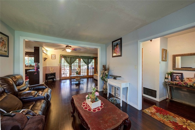 living room with ceiling fan, dark wood-type flooring, and a textured ceiling