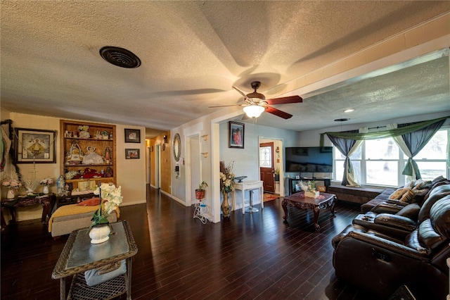 living room featuring dark hardwood / wood-style floors, a textured ceiling, and ceiling fan