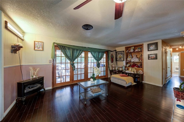 living room featuring dark hardwood / wood-style floors, ceiling fan, and a textured ceiling