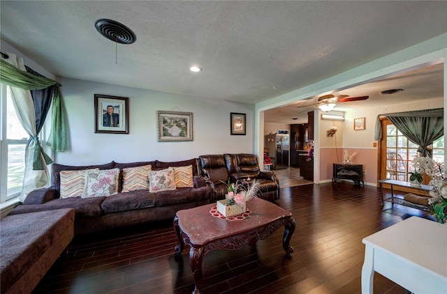 living room with dark hardwood / wood-style flooring, ceiling fan, and a textured ceiling