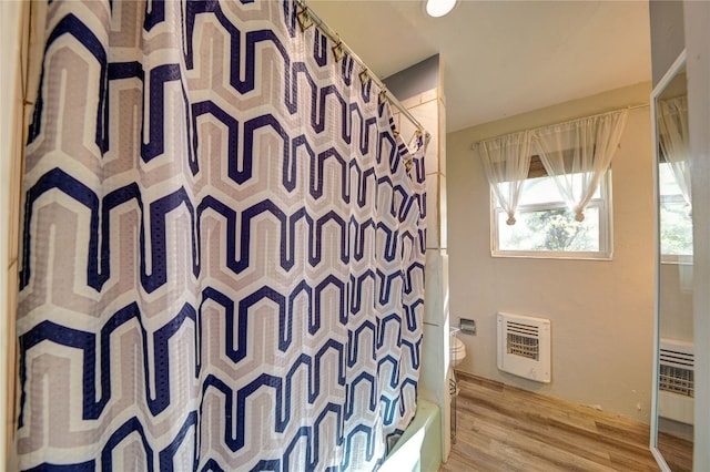 bathroom featuring hardwood / wood-style floors, shower / bathtub combination with curtain, and toilet