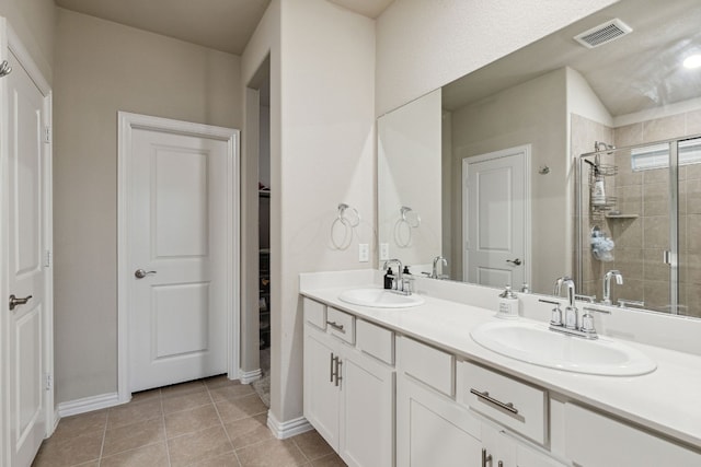 bathroom with double sink, a shower with door, tile flooring, and large vanity