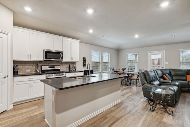 kitchen with light hardwood / wood-style flooring, a center island with sink, stainless steel appliances, white cabinetry, and sink