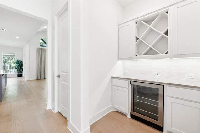 bar featuring white cabinets, backsplash, wine cooler, and light hardwood / wood-style flooring