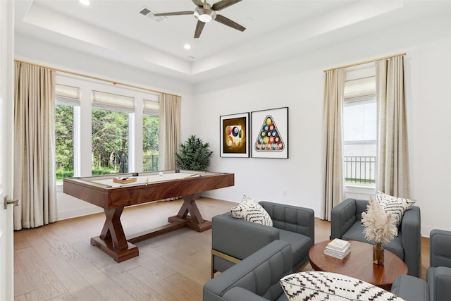 playroom featuring a tray ceiling, ceiling fan, and light hardwood / wood-style flooring