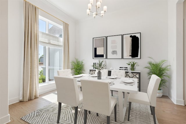 dining space featuring light hardwood / wood-style flooring, ornamental molding, and a notable chandelier