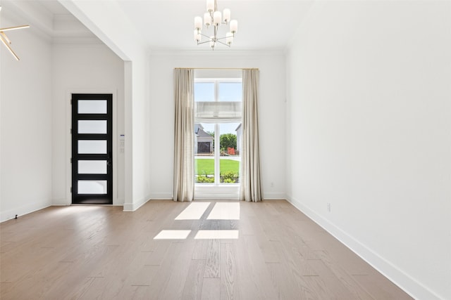 foyer entrance featuring light wood-type flooring, crown molding, and a notable chandelier