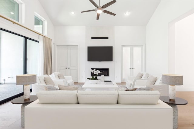 living room featuring french doors, light hardwood / wood-style flooring, high vaulted ceiling, and ceiling fan