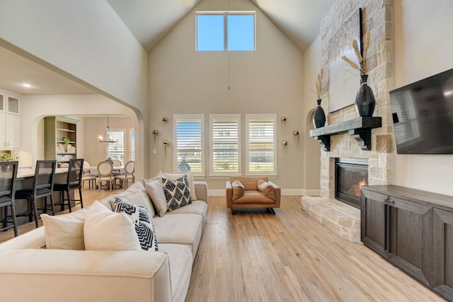 living room with a towering ceiling, light hardwood / wood-style flooring, and a fireplace