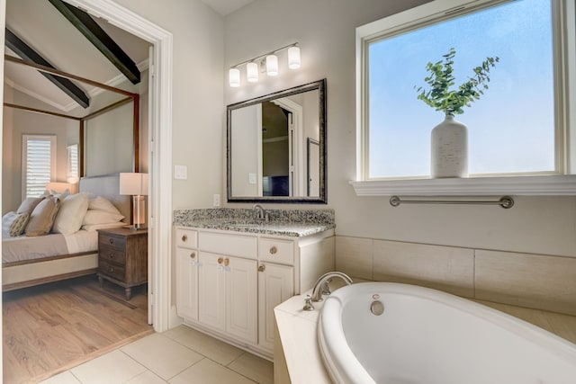 bathroom with vanity, tiled tub, tile patterned floors, and lofted ceiling