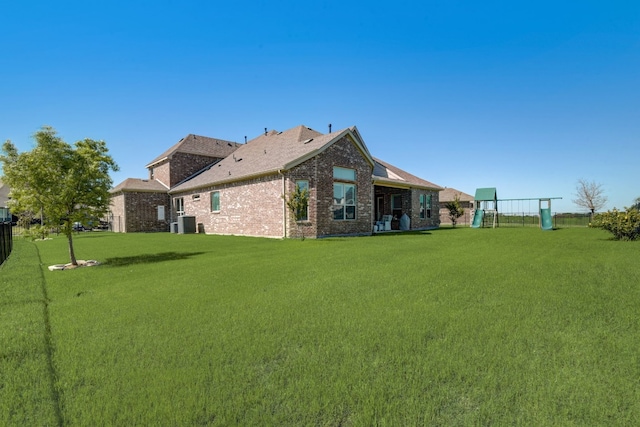 back of house with a playground and a lawn