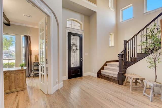 entrance foyer with crown molding and light hardwood / wood-style floors